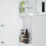 Preparazione detergenti bagno in armadietto a muro, mobili di colore bianco.