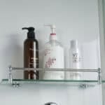 Prodotti per la cura della pelle e dei capelli, in dispenser e flaconi su mensola in bagno.