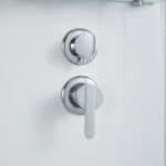 Lavabo di design con due maniglie cromate, in un ambiente elegante e minimalista.