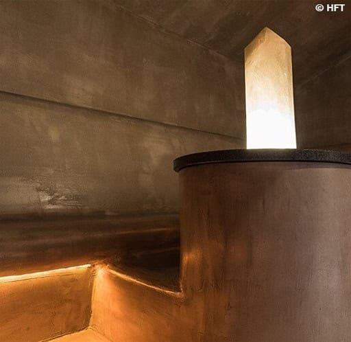 Bagnoturco_13 Piscina coperta con pareti in pietra, illuminazione soffusa e ambiente rilassante.