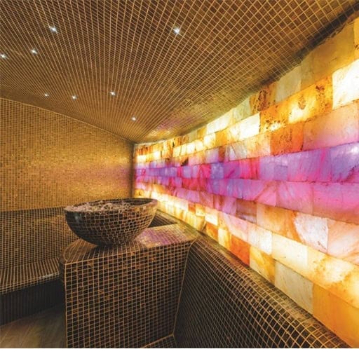 Bagnoturco_2 Piscina coperta con pareti di sale rosa e sedute in mosaico, ambiente rilassante e accogliente.