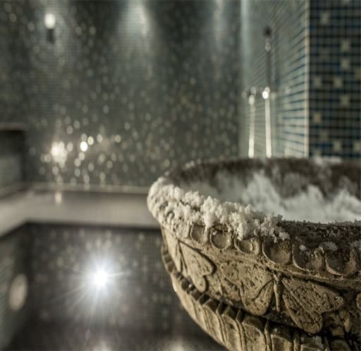 Bagnoturco_5 Una vasca termale in pietra, immersa in un ambiente wellness caldo e rilassante.