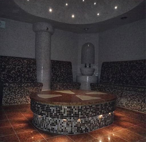 Bagnoturco_6 Piscina coperta con rivestimento mosaico e zona relax, ideale per il benessere e il relax in ambienti interni eleganti.