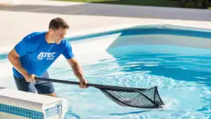 Bild3 Piscina interrata con acqua limpida, operatore di Atec Pool Sagl pulisce la vasca con un'asta e rete.