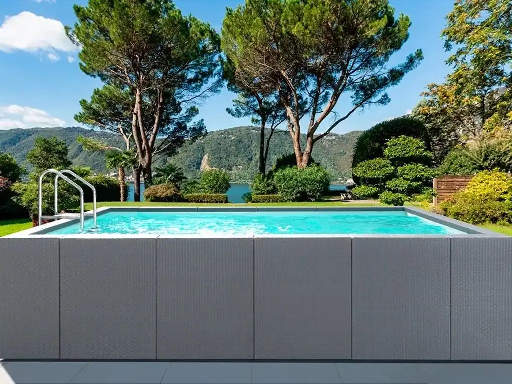Piscina interrata con bordo a sfioro immersa nel verde con vista su montagne e lago, ambiente rilassante e naturale.