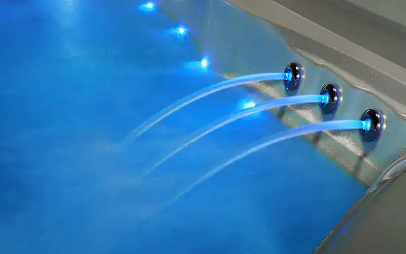 Piscina con getti d'acqua e illuminazione LED blu, ambiente wellness. Piscina con getti d'acqua e luci LED blu, ambiente wellness.